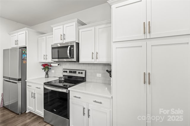 kitchen with dark hardwood / wood-style flooring, appliances with stainless steel finishes, decorative backsplash, and white cabinetry