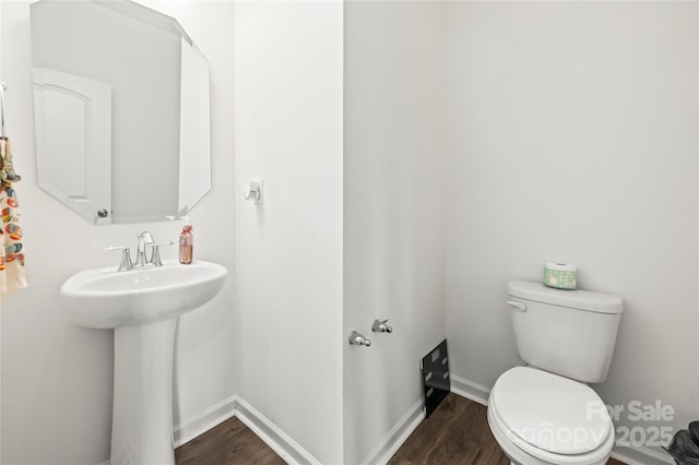 bathroom featuring toilet, wood-type flooring, and sink