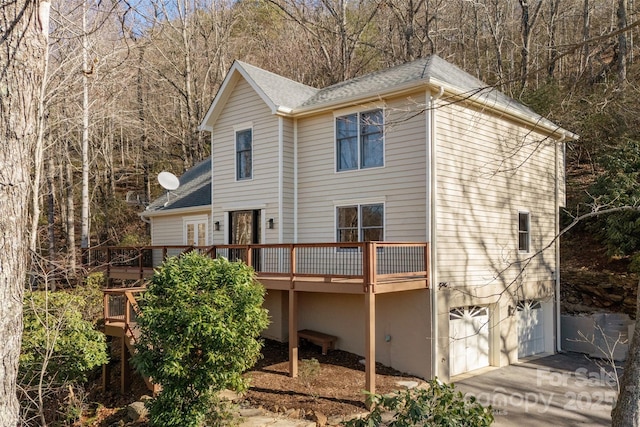 back of property featuring a wooden deck and a garage