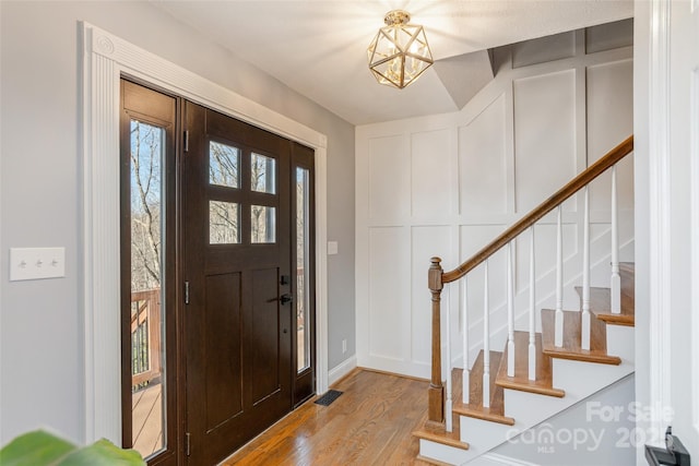 foyer entrance with light wood-type flooring and a notable chandelier