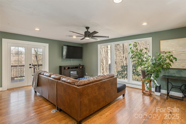 living room featuring french doors, light hardwood / wood-style flooring, ceiling fan, and a healthy amount of sunlight