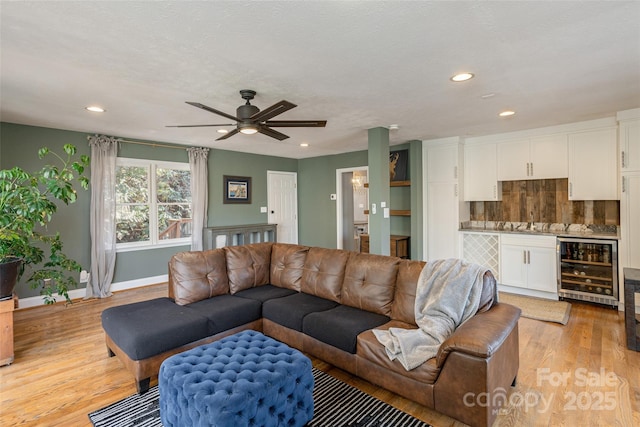 living room featuring ceiling fan, a textured ceiling, beverage cooler, and light hardwood / wood-style flooring