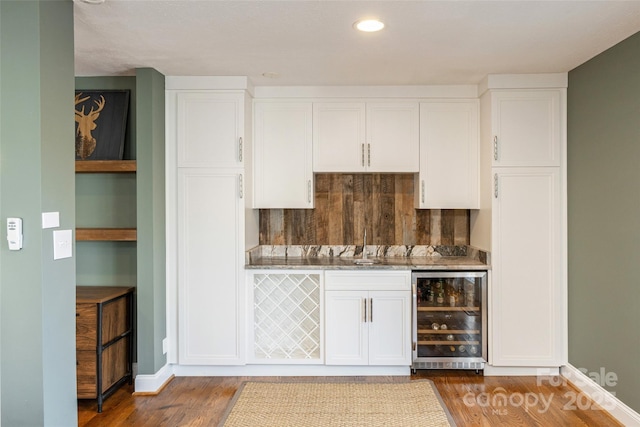 bar featuring white cabinetry, dark hardwood / wood-style flooring, and beverage cooler