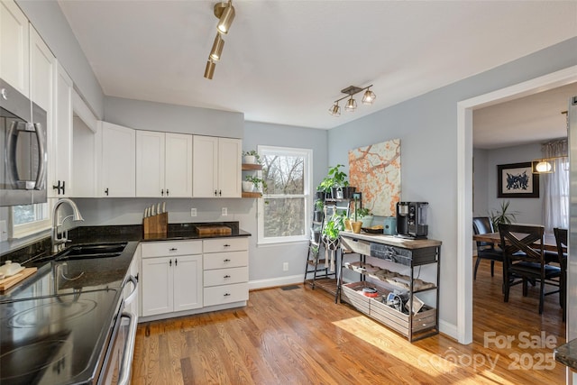 kitchen with white cabinets, sink, and light hardwood / wood-style flooring