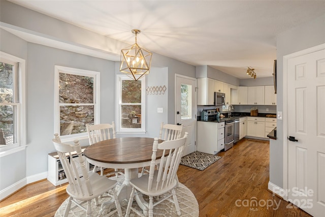 dining room featuring a healthy amount of sunlight, an inviting chandelier, and dark wood-type flooring