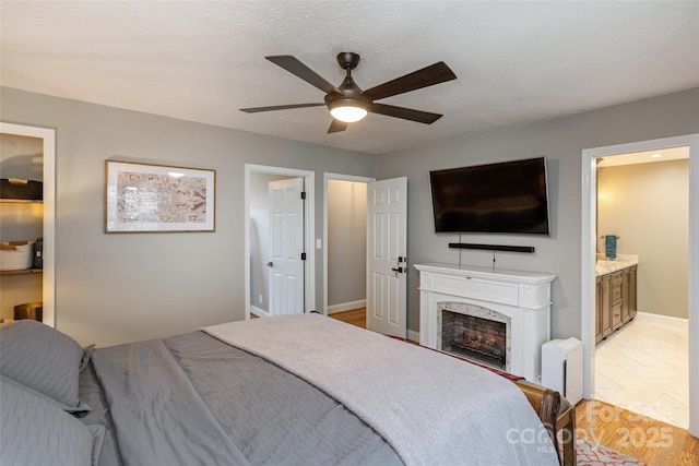 tiled bedroom featuring ensuite bathroom and ceiling fan