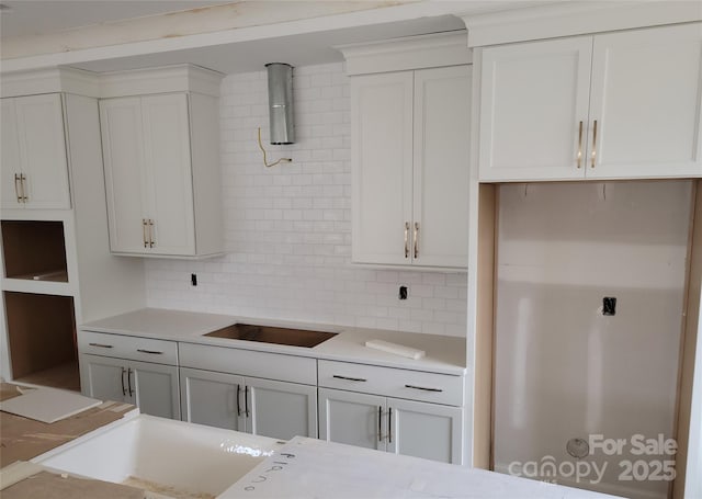 kitchen featuring backsplash, white cabinets, light countertops, and black electric stovetop