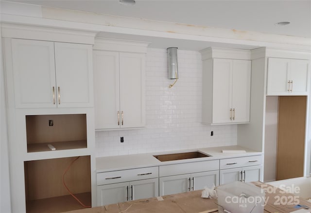 kitchen with backsplash, white cabinets, light countertops, and black electric stovetop