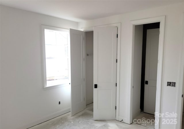 unfurnished bedroom featuring unfinished concrete flooring and baseboards