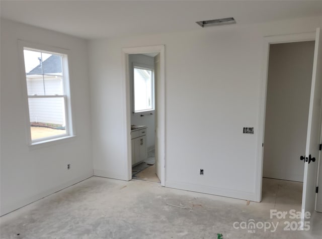 unfurnished bedroom with connected bathroom and baseboards