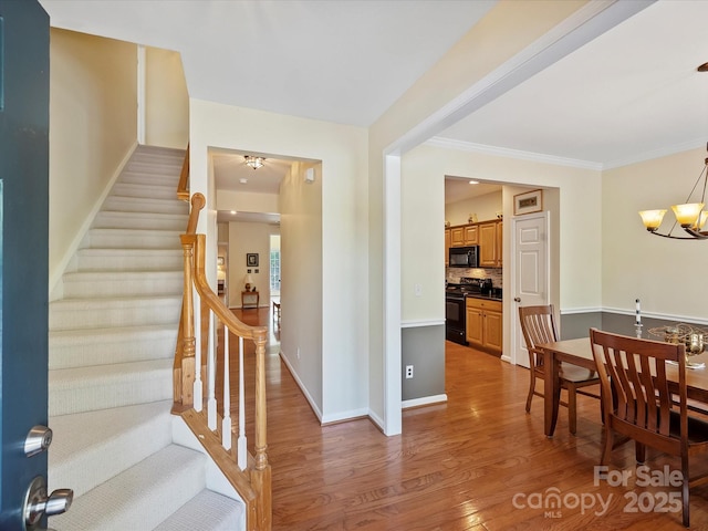 interior space featuring hardwood / wood-style flooring, crown molding, and an inviting chandelier