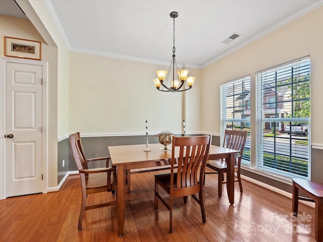 dining room featuring hardwood / wood-style floors, an inviting chandelier, and crown molding