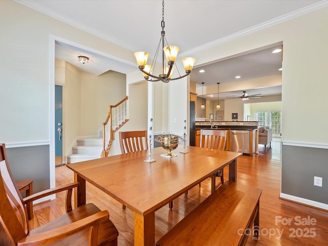 dining area featuring ceiling fan with notable chandelier, light hardwood / wood-style floors, sink, and crown molding