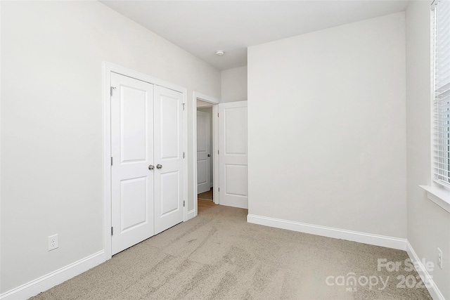 unfurnished bedroom with light carpet and a closet