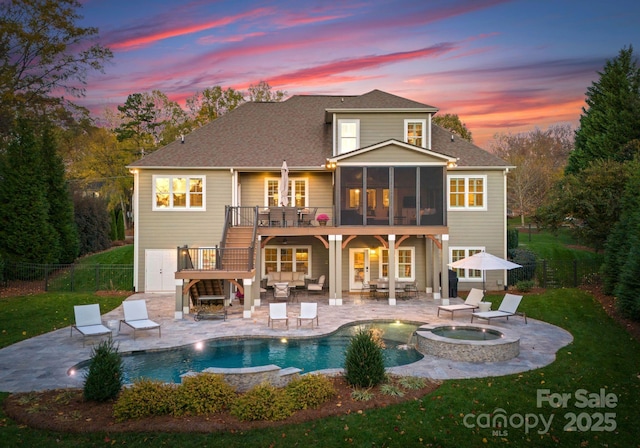 back house at dusk featuring an outdoor hangout area, a pool with hot tub, a patio area, and a sunroom