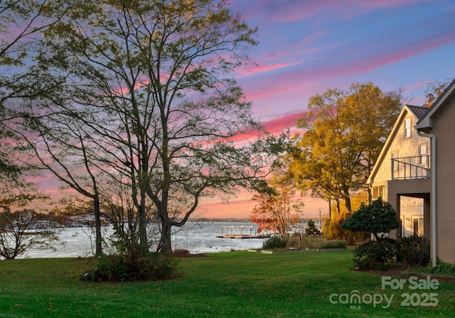 yard at dusk with a water view and a balcony