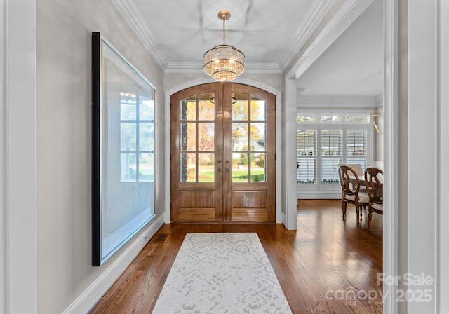 entryway featuring ornamental molding, dark hardwood / wood-style flooring, a chandelier, and french doors