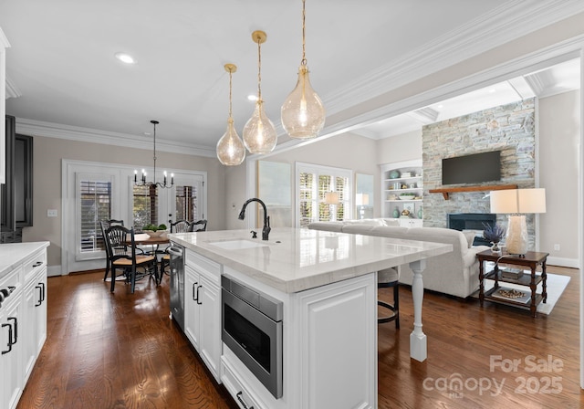 kitchen featuring appliances with stainless steel finishes, pendant lighting, sink, white cabinets, and a kitchen island with sink