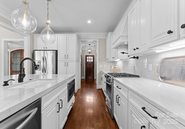 kitchen with appliances with stainless steel finishes, pendant lighting, sink, white cabinets, and light stone counters