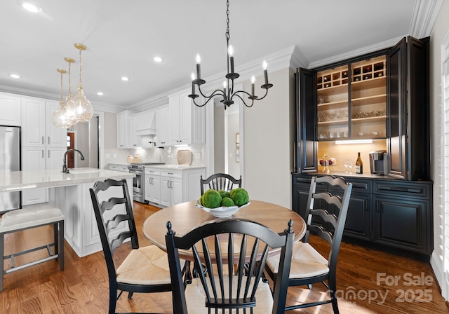 dining area with crown molding, sink, and dark hardwood / wood-style floors