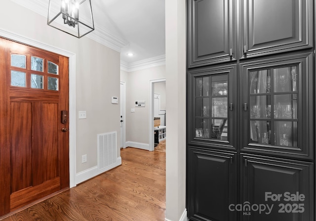 entrance foyer with crown molding and hardwood / wood-style floors