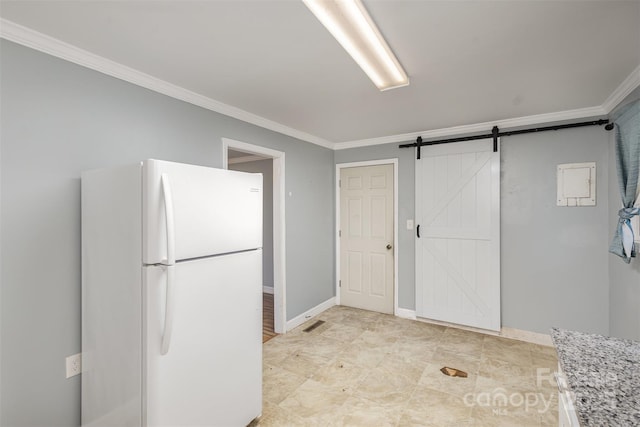 interior space with light stone countertops, a barn door, white fridge, and crown molding