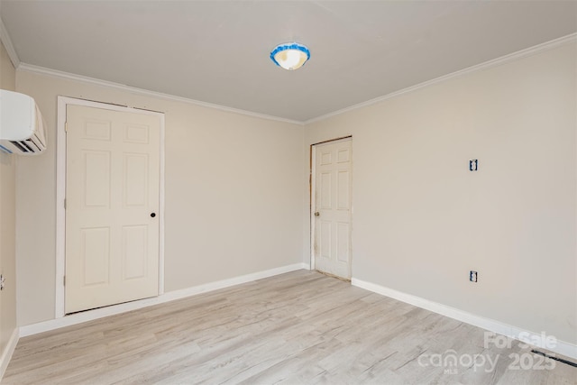 empty room featuring crown molding, a wall mounted air conditioner, and light wood-type flooring