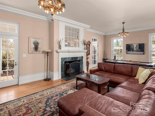 living room featuring hardwood / wood-style floors, a premium fireplace, ornamental molding, and a chandelier