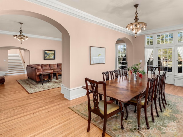 dining room featuring light wood-type flooring, crown molding, and a notable chandelier