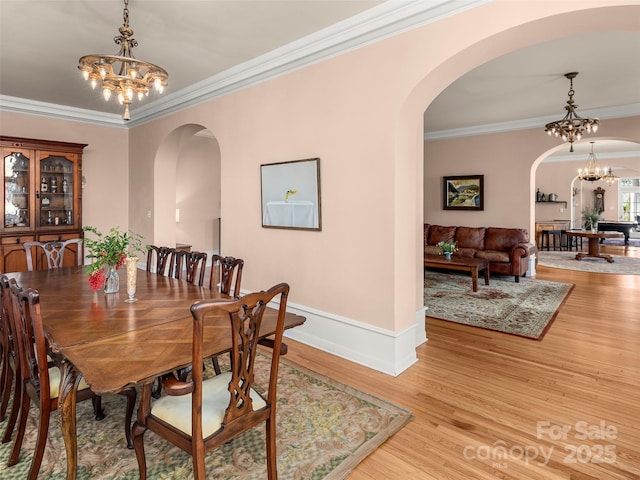 dining space with a notable chandelier, light hardwood / wood-style floors, and crown molding