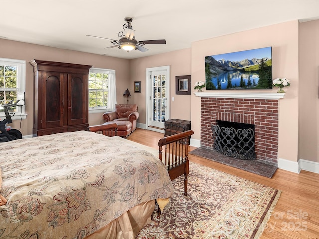 bedroom featuring ceiling fan, access to exterior, light wood-type flooring, and a fireplace