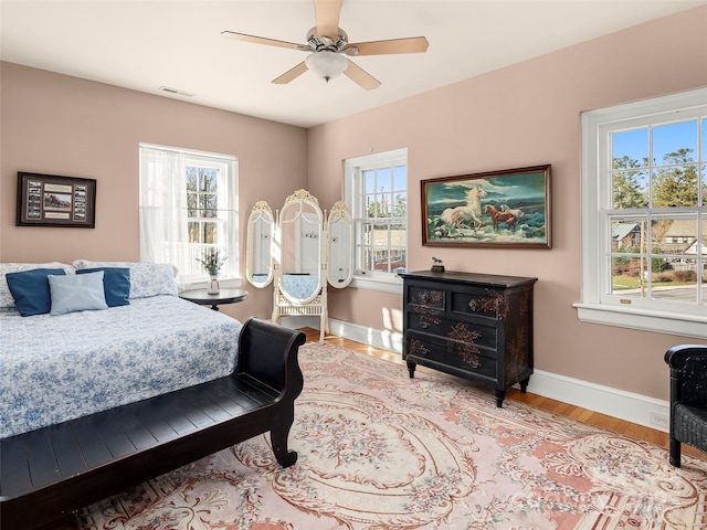 bedroom featuring ceiling fan, light wood-type flooring, and multiple windows