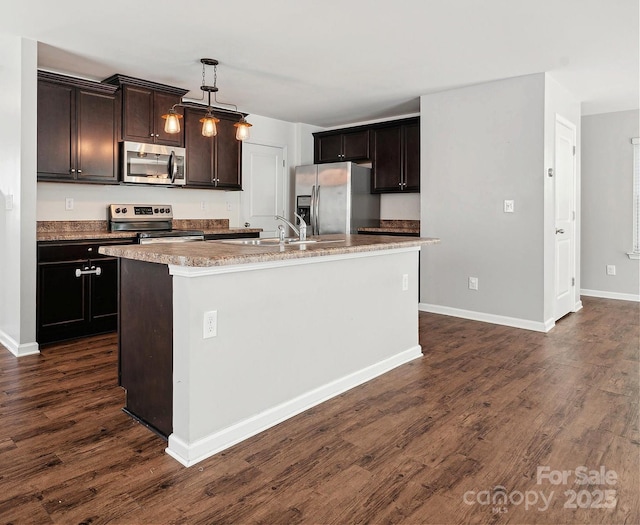 kitchen with sink, an island with sink, appliances with stainless steel finishes, decorative light fixtures, and dark hardwood / wood-style flooring