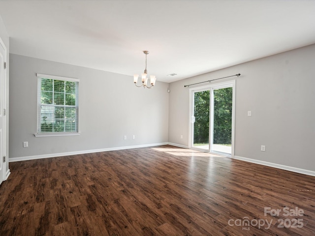 empty room with a chandelier and dark hardwood / wood-style floors