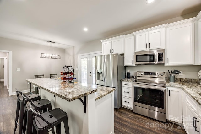 kitchen with a kitchen island, white cabinetry, stainless steel appliances, and a breakfast bar area