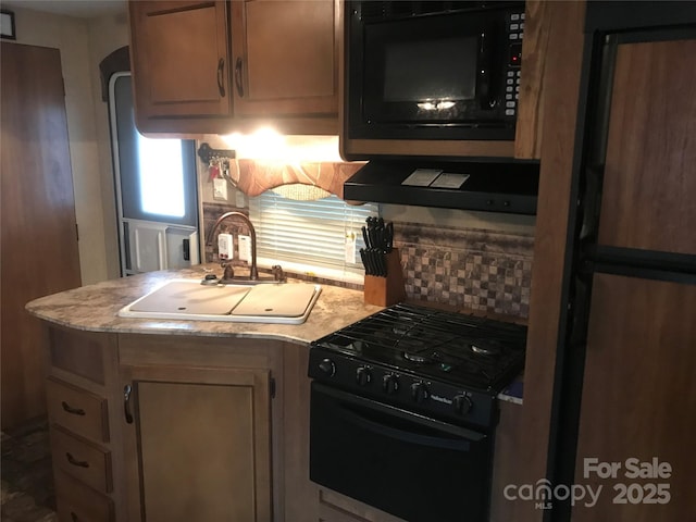 kitchen featuring black appliances, ventilation hood, and sink