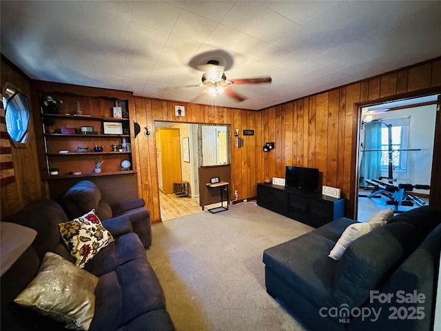 living room featuring ceiling fan, built in features, and light colored carpet