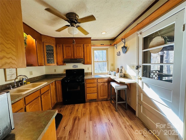 kitchen with gas stove, ceiling fan, sink, a textured ceiling, and light wood-type flooring