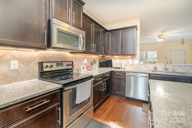 kitchen with ceiling fan, sink, dark wood-type flooring, stainless steel appliances, and dark brown cabinets