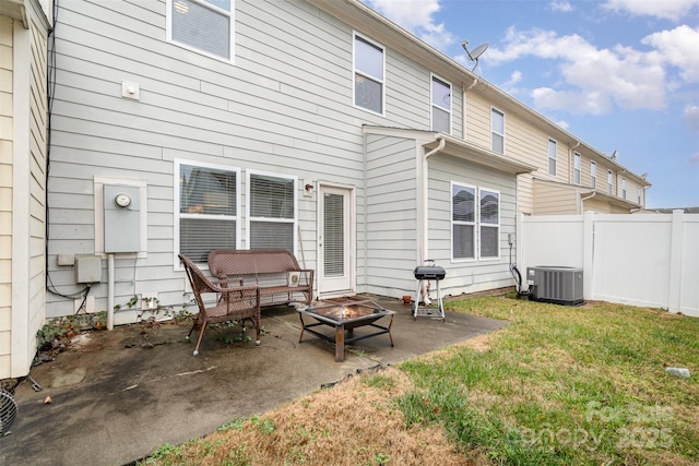 rear view of property with central AC, a yard, a patio, and a fire pit