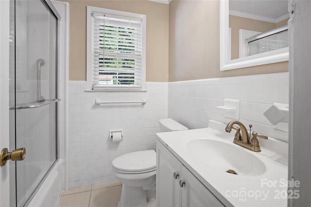 full bathroom featuring vanity, shower / bath combination with glass door, tile walls, tile patterned flooring, and toilet