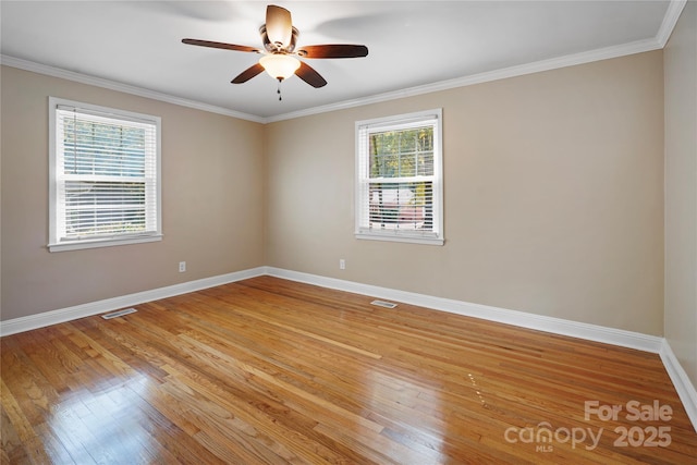 empty room featuring light hardwood / wood-style flooring, a wealth of natural light, and ornamental molding