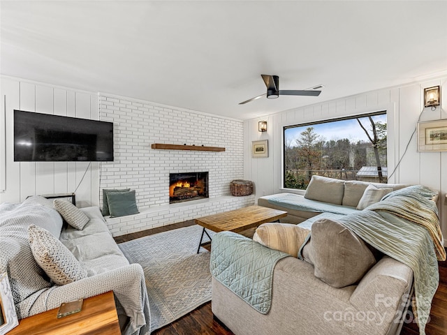 living room with ceiling fan, a fireplace, and dark wood-type flooring