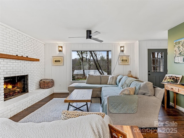 living room with ceiling fan, wood walls, dark hardwood / wood-style floors, and a brick fireplace