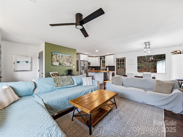 living room with dark hardwood / wood-style flooring and ceiling fan with notable chandelier