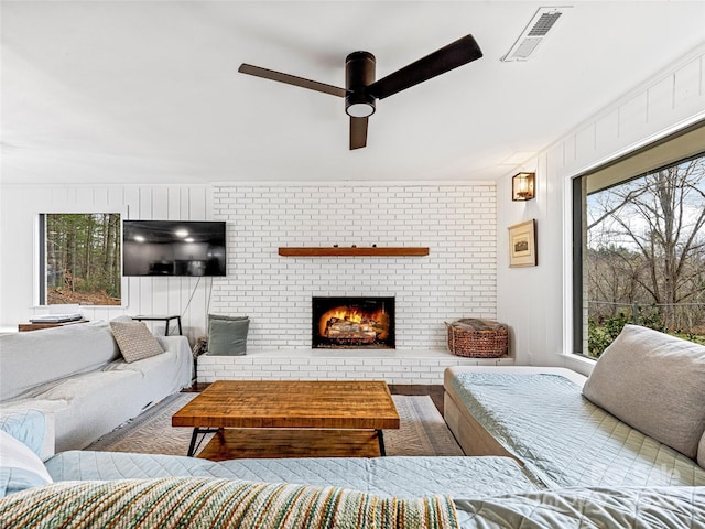 living room with ceiling fan and a fireplace