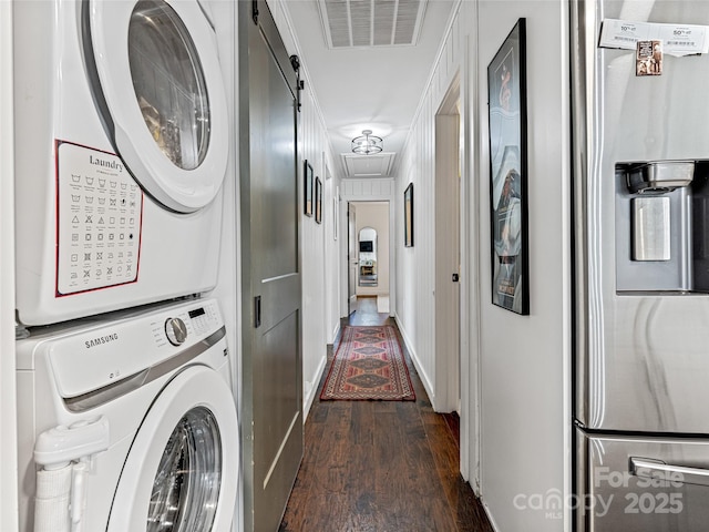 laundry area with a barn door, dark hardwood / wood-style flooring, stacked washing maching and dryer, and ornamental molding