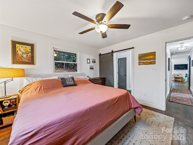 bedroom featuring a barn door, light hardwood / wood-style floors, and ceiling fan