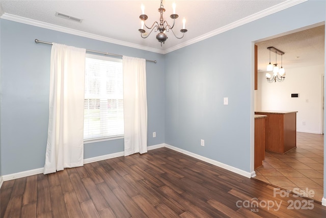 spare room featuring dark hardwood / wood-style floors, ornamental molding, a textured ceiling, and a chandelier