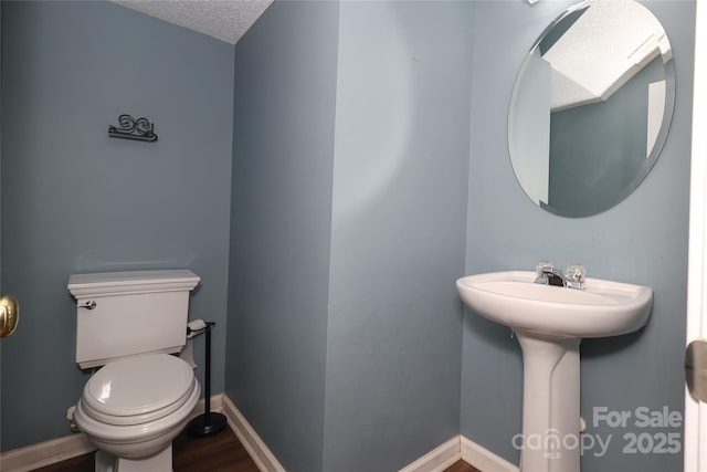 bathroom with wood-type flooring, a textured ceiling, and toilet